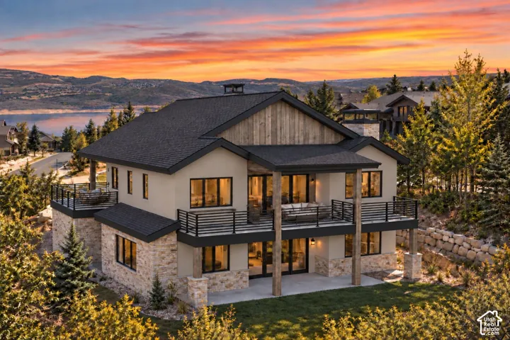 Multi-level mountain residence featuring stone veneer siding, timber support beams, multi-level exterior decks with metal railings, and a prominent asphalt shingle roof