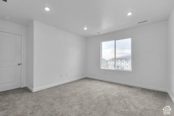 Plush gray carpeting, white walls, recessed ceiling lighting, and a double-pane window
