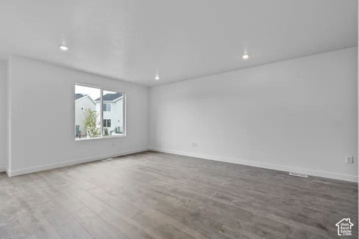 Window-framed exterior views, overhead recessed lighting, smooth white walls, and wood-finish flooring