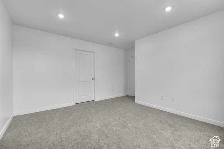 Recessed lighting, grey carpet flooring, white walls, and white two-panel interior doors
