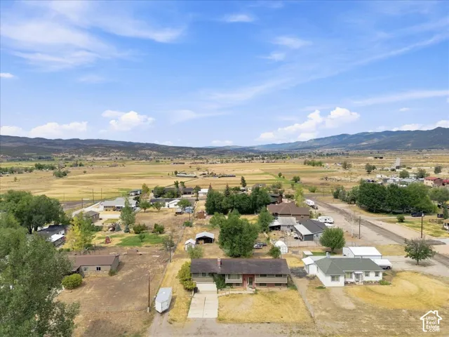 Expansive rural landscape with distant mountains, visible agricultural fields, and a residential property with an attached garage