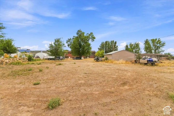 Expansive undeveloped lot with mature trees and a metal outbuilding