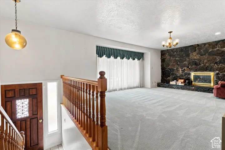 Hardwood stair railing and balusters, dark wood entry door with decorative glass, full-height sidelight, stone-clad fireplace, and recessed fireplace insert
