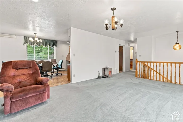 Carpeted living area with a wood baluster railing and a suspended chandelier