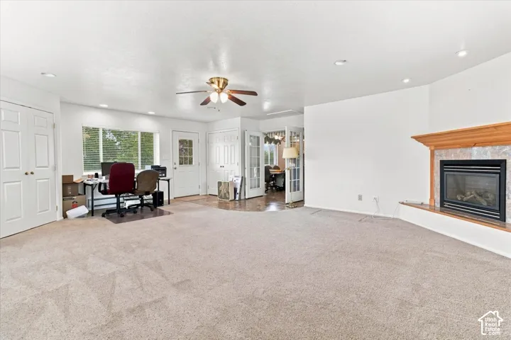 Recessed lighting, ceiling fan, fireplace with wood mantel and tile surround, French doors, and wood-finish flooring