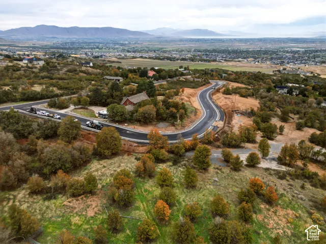 Expansive undeveloped land with a newly paved road, surrounded by deciduous trees and distant mountain ranges