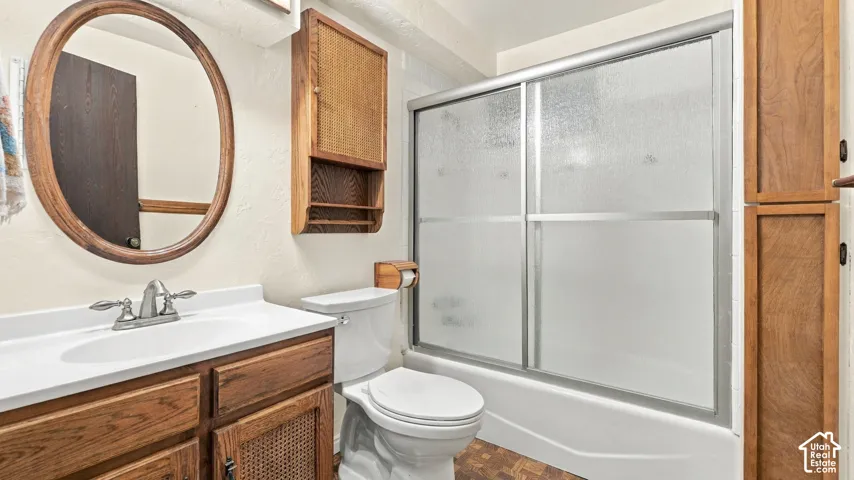 Bathroom featuring a wood-finish vanity with an integrated basin, oval wall-mounted mirror, built-in wooden cabinetry, and a shower-tub combination with sliding glass doors