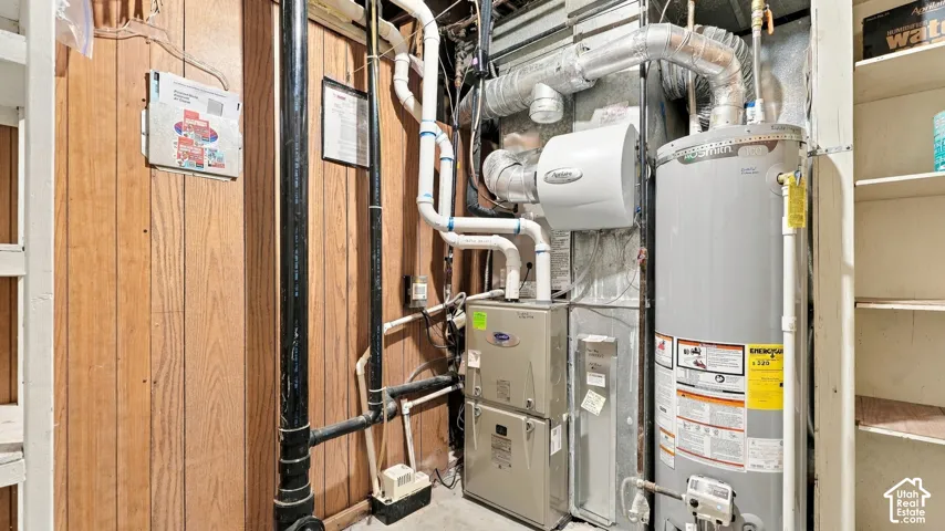 Mechanical utility area featuring a furnace, water heater, mounted air filtration system, and integrated shelving