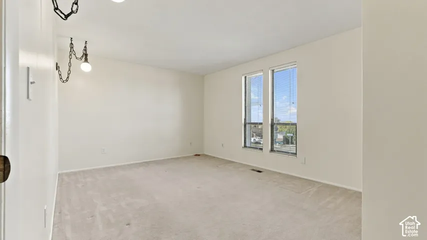 Interior space featuring wall-to-wall carpeting, neutral-toned walls, and dual-pane vertical windows with integrated blinds