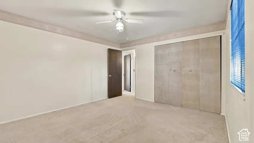 Interior space featuring wall-to-wall carpeting, a ceiling fan with integrated lighting, and sliding closet doors