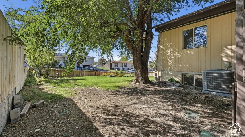 Backyard featuring vertical siding, wooden privacy fencing, mature landscaping, and an exterior HVAC unit