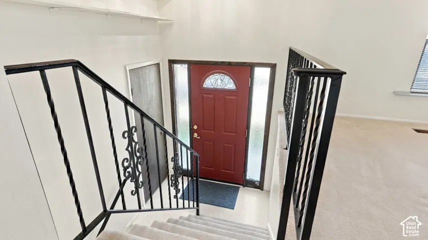 Entryway featuring a solid door with an arched glass insert, dual vertical sidelights, and black iron railings with decorative metalwork
