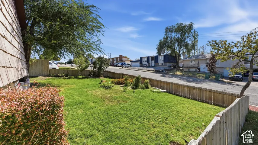 Side yard featuring a grass lawn, mature trees, and wood fencing