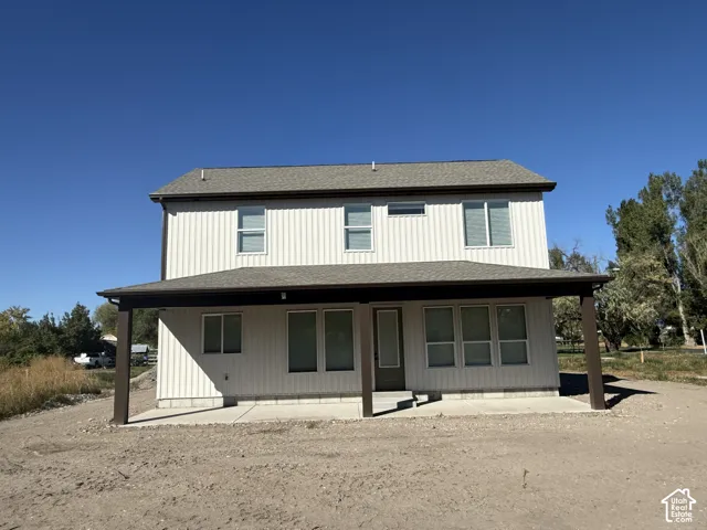 Two-story exterior with vertical siding, covered patio, dark roof, and multiple windows