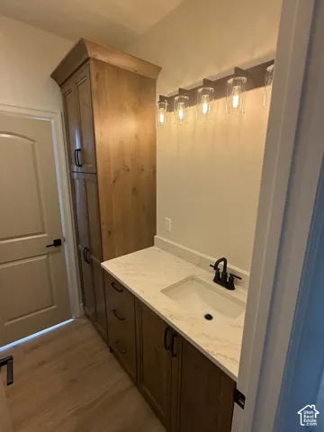 Built-in cabinetry with a light wood finish, white countertop, integrated sink, and black faucet