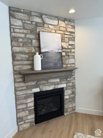 Corner-set fireplace with natural stone surround, a wood-finish mantel, and a black firebox