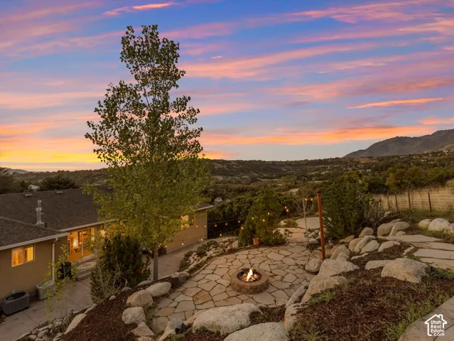 Expansive outdoor living area featuring a flagstone patio, built-in fire pit, and surrounding natural rock landscaping