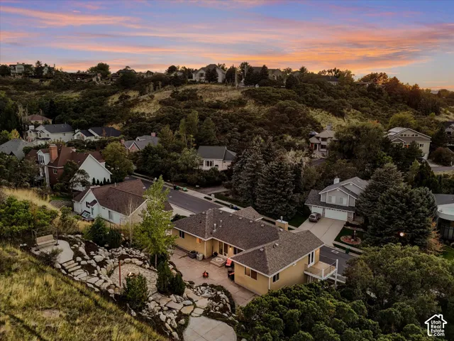 Terraced landscaping with stone steps, a dedicated fire pit area, a private deck, and an attached two-car garage