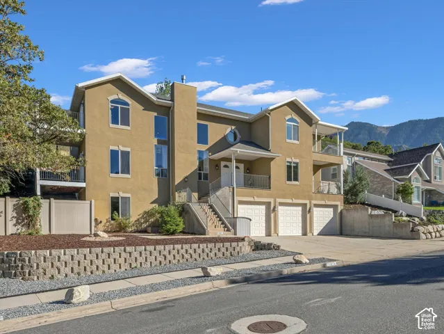 Stucco exterior residence featuring multiple balconies, arched windows, and a three-car garage