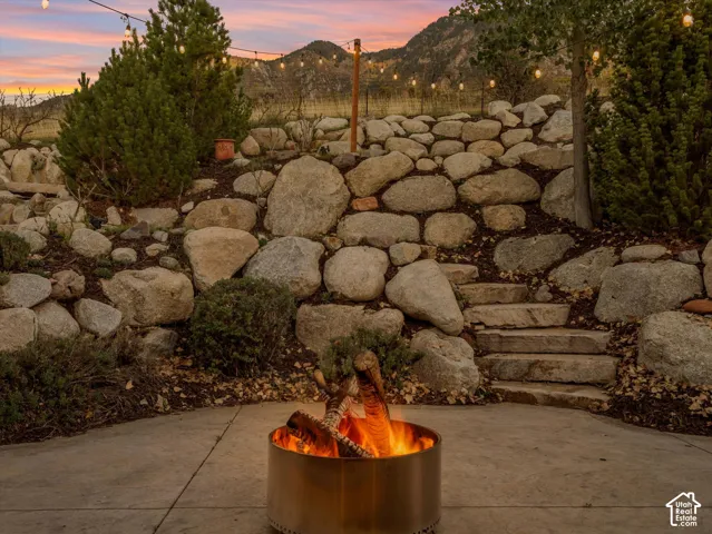 Stone retaining wall with built-in stone steps, featuring string lighting and a mountain backdrop
