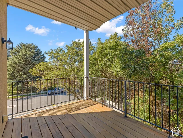 Balcony with wood-finish decking, black metal railings, and a corrugated metal ceiling