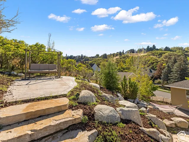 Concrete patio space with natural stone steps, surrounded by landscaped rockery and mature trees