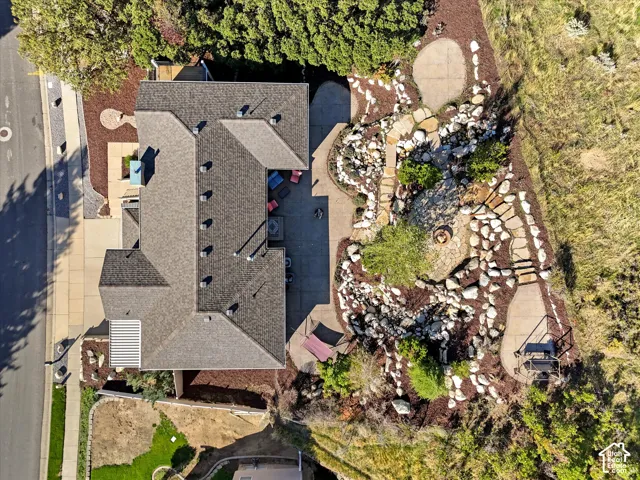 Multi-level exterior with a shingled roof, extensive hardscaping, stone pathways, and a built-in fire pit