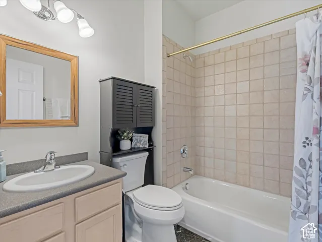 Bathroom featuring a vanity with an integrated sink, a wood-framed mirror, a built-in toilet cabinet, a toilet, and a bathtub with tiled surround