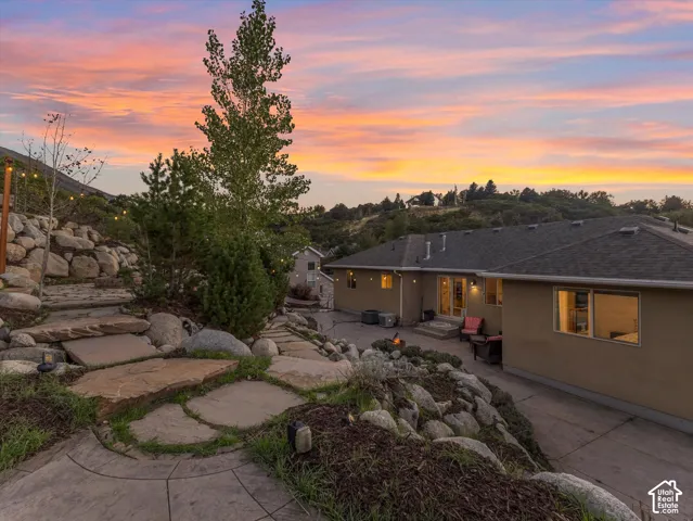 Stone retaining walls with integrated plantings, concrete patio, concrete driveway, and landscape lighting