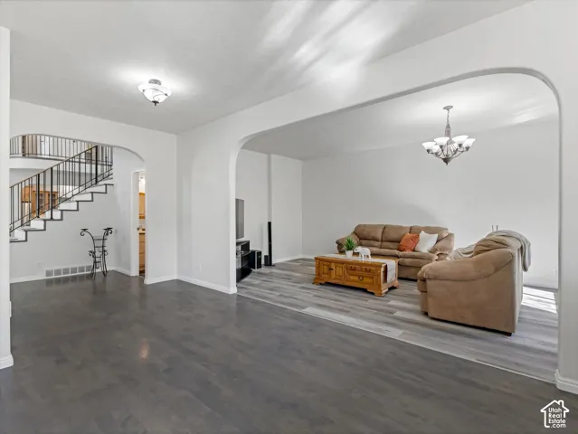 Spacious open-concept living area featuring dark wood-finish flooring, soaring ceilings with recessed lighting, and an arched entryway with custom millwork