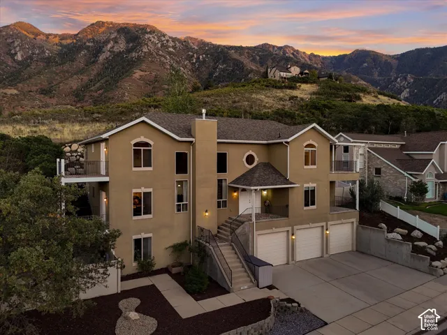 Multi-level residence featuring a stucco exterior, multiple balconies, a three-car garage, and a covered entry