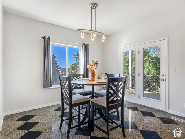 Dining area featuring a round wood-finish table, black X-back chairs with cushioned seats, and a geometric patterned concrete floor with inlaid diamond detailing