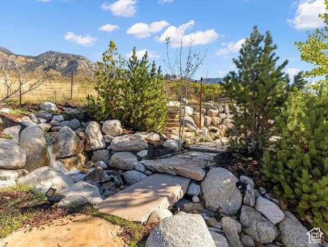 Landscaped rock garden with a stone bridge, water feature, and terraced stone retaining walls