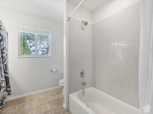 Bright bathroom featuring white subway tile surround, chrome fixtures, and a classic white bathtub with integrated shower