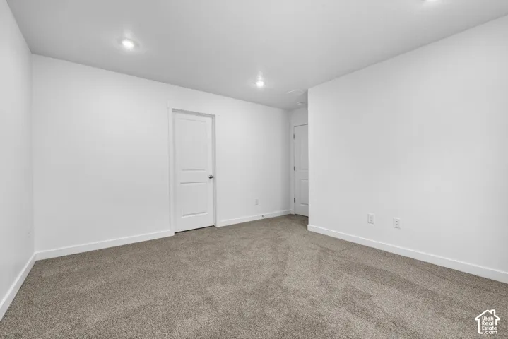 Recessed lighting, white interior doors, neutral wall paint, and gray carpet flooring