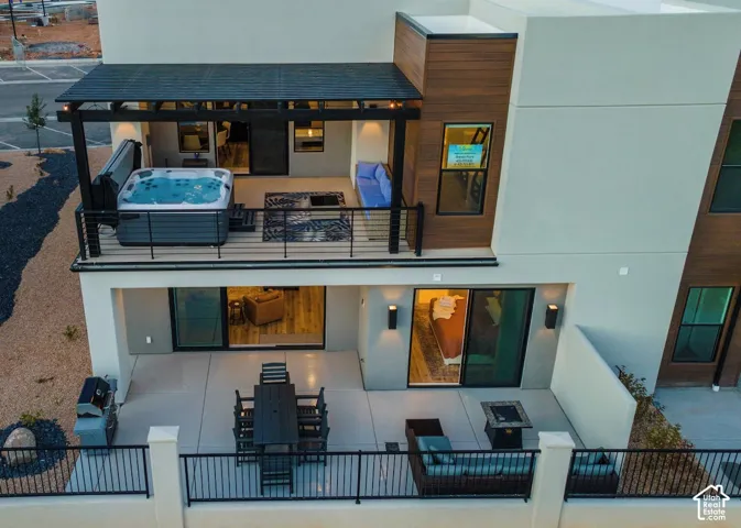 Multi-level exterior featuring a private hot tub, covered patio, and balcony