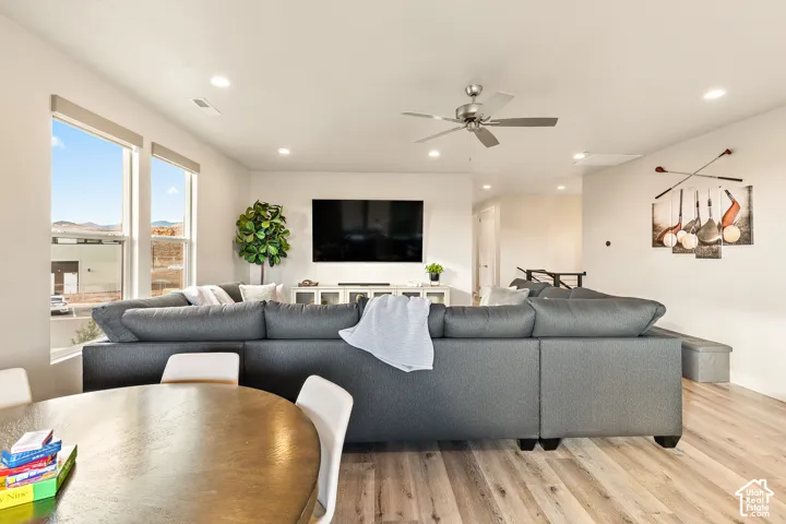 Bright living area with large windows, recessed lighting, wood-finish flooring, and a ceiling fan