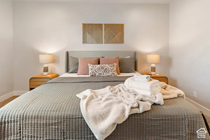 Upholstered headboard with two integrated wall sconces, wood-finish nightstands, and light-toned wall paint