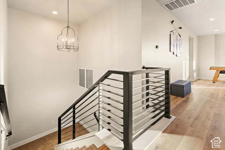 Modern metal and wood railing system, contemporary chandelier, recessed lighting, and wood-finish flooring
