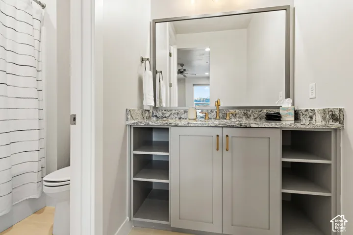 Vanity with a stone countertop, dual-door cabinetry, and open shelving