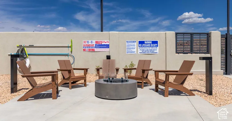 Concrete patio with a central gas fire pit, surrounded by Adirondack-style chairs