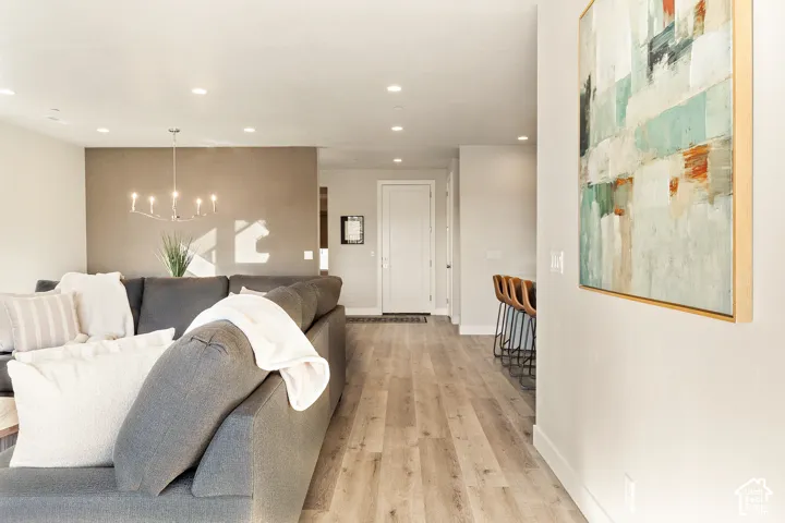 Recessed lighting, wood-finish flooring, and a modern chandelier