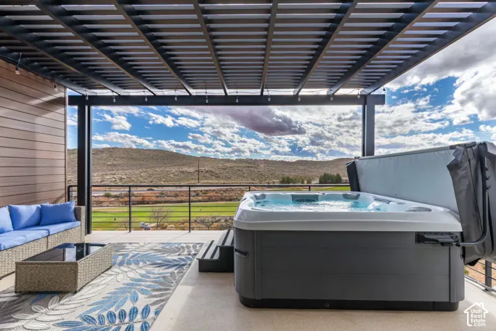 Covered patio featuring a hot tub, slatted ceiling structure, exterior siding, and metal railings
