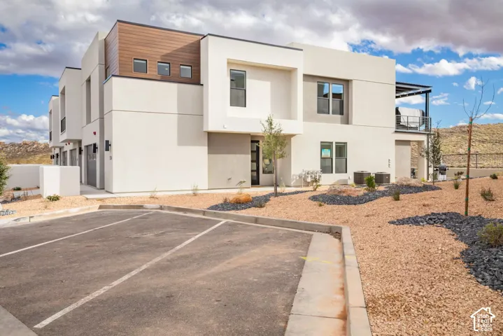 Modern exterior featuring clean lines, wood-finish accents, multiple windows, and a balcony with metal railings