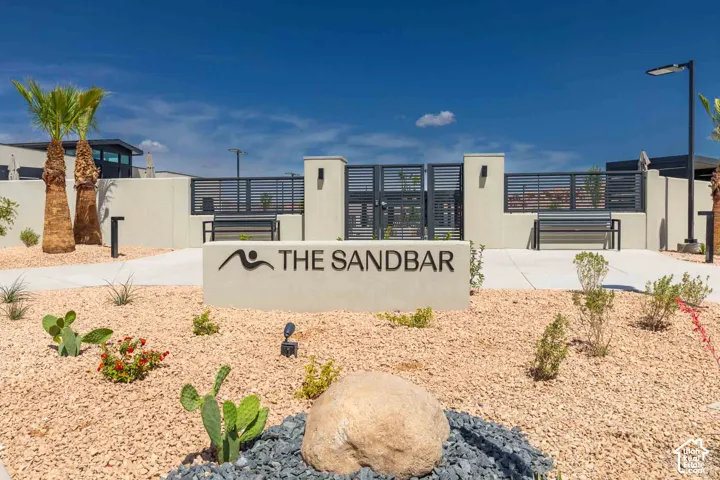 Entry monument with signage, desert landscaping, palm trees, and perimeter fencing