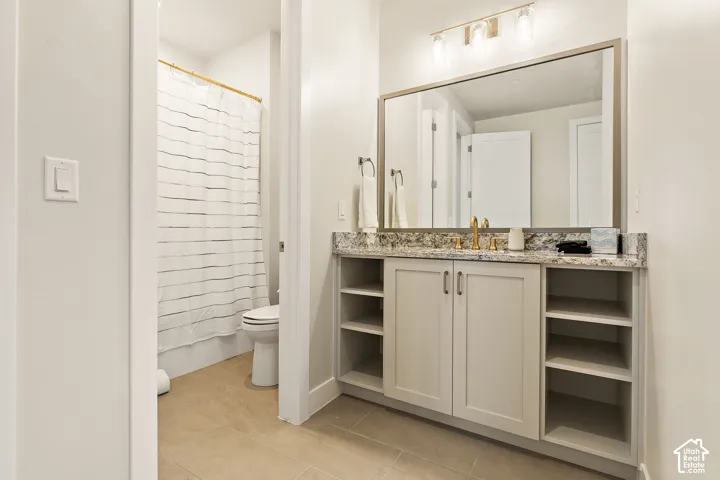 Vanity with light-colored cabinetry, stone-finish countertop, and gold-tone hardware