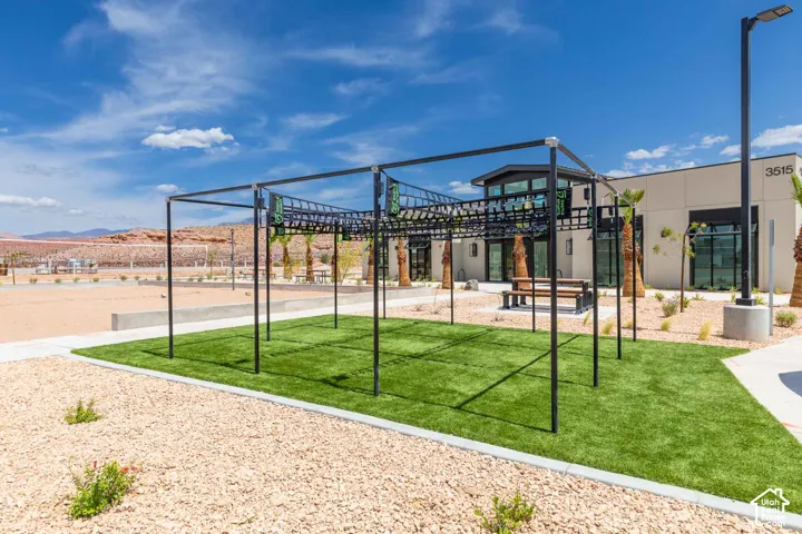 Artificial turf area with an overhead monkey bar structure, surrounded by gravel landscaping