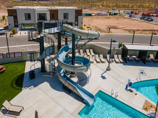 Resort-style pool with a water slide, integrated basketball hoop, and poolside cabanas