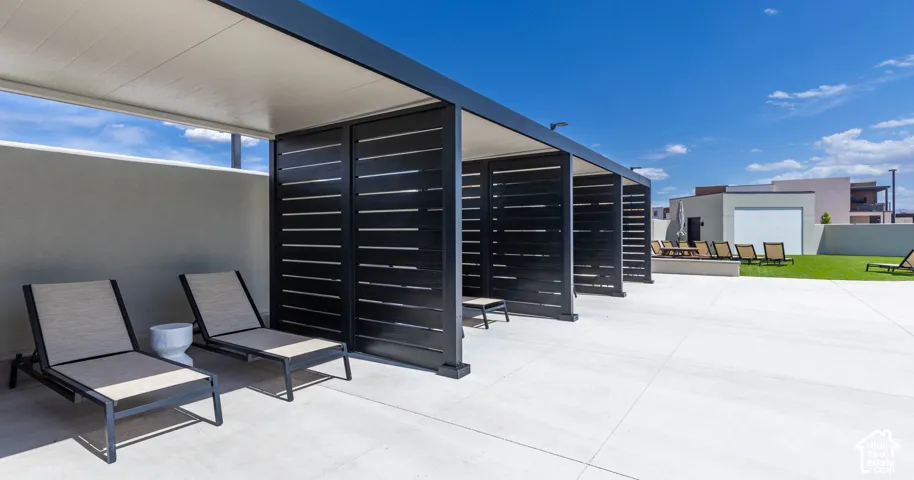 Shaded lounge areas with privacy screens, expansive hardscaping, and a synthetic lawn area