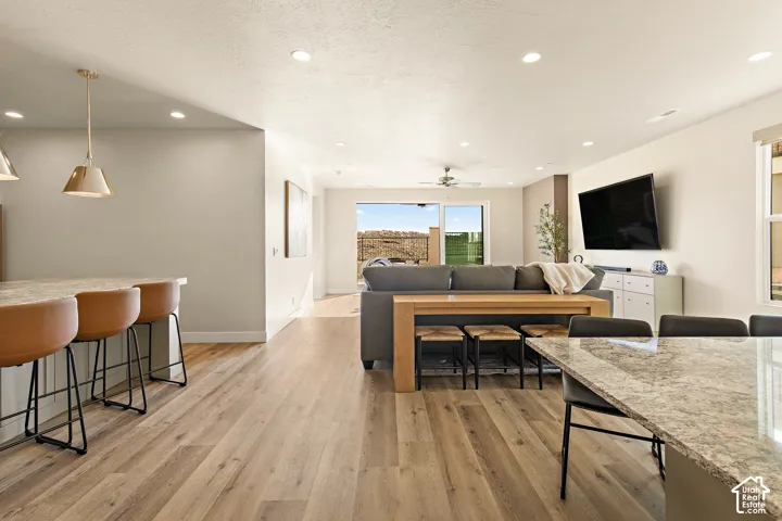 Open-concept living area with wood-finish flooring, recessed lighting, and a ceiling fan
